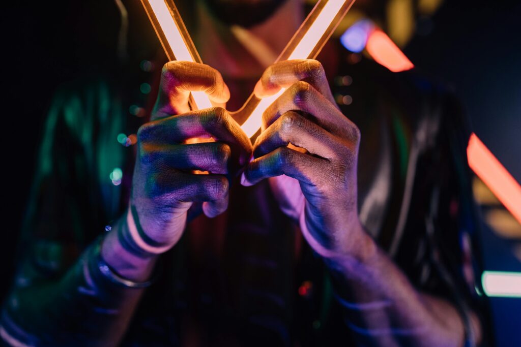 pexels-photo-6940576-6940576 Colorful neon lights illuminating hands in a vibrant nightlife setting.