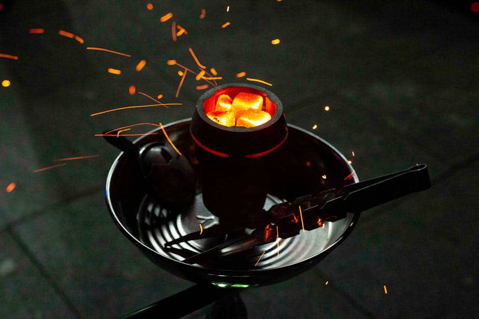 Close-up of glowing hookah coals with sparks in a dark setting, emphasizing warmth and relaxation.